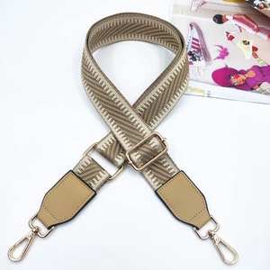 Detail of adjustable geometric woven strap with gold metal hooks and leather trim