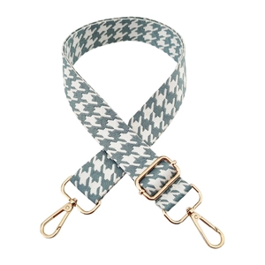 Detailed view of houndstooth embroidery strap with golden metal swivel hooks and buckles