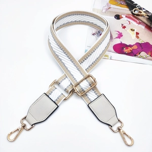 Detail of adjustable woven bag strap with golden lobster clasps and grey leather ends