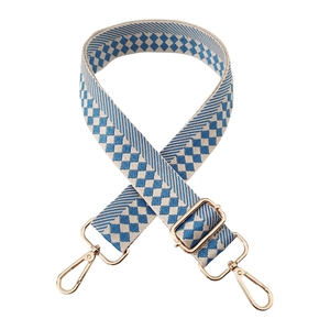 Detail of blue and white checkered jacquard bag strap with gold metal lobster clasps
