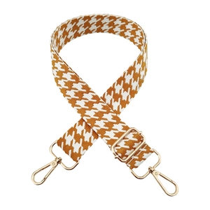 Detail of adjustable houndstooth bag strap with gold metal lobster clasps and buckles
