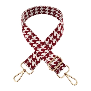 Detailed texture of red houndstooth jacquard strap with gold-tone metal hooks