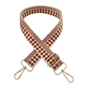Detail of adjustable checkered wide shoulder strap with golden metal swivel hooks