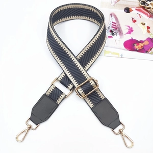 Detail of adjustable woven herringbone bag strap with faux leather ends and gold metal clasps