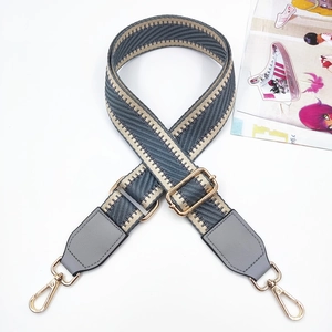 Detail of grey herringbone strap with golden metal hooks and adjustable buckle for bags