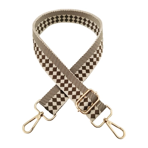 Detail of checkered woven bag strap with golden metal swivel hooks and adjustable buckle