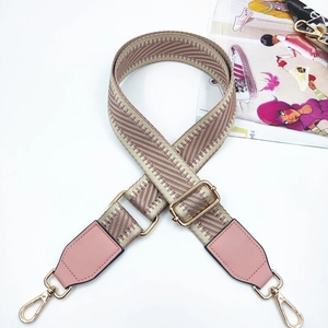 Detail of adjustable bag strap with beige chevron weave and gold metal swivel hooks