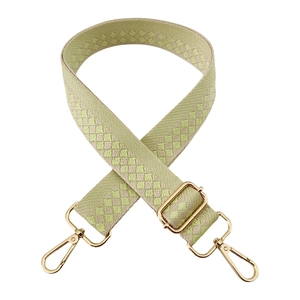 Close-up of adjustable checkerboard strap with gold metal hooks and green fabric texture