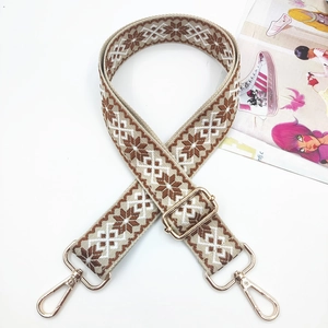 Detail of embroidered geometric pattern and golden metal buckles on adjustable bag strap