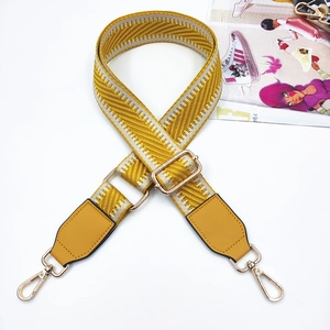 Detail of adjustable yellow herringbone strap with gold metal hooks for handbags