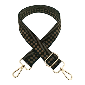 Detail of checkered woven wide bag strap with gold metal lobster clasps and buckles