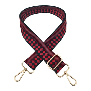 Detail of red and black checkered woven strap with light gold metal lobster clasps
