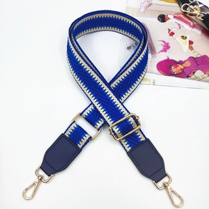 Detail of adjustable blue geometric woven bag strap with gold metal buckles and swivel hooks