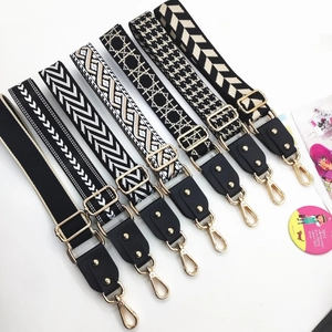 Close-up of woven wide bag straps with geometric patterns and gold metal buckles