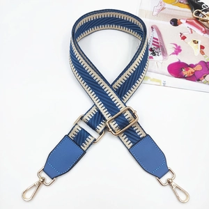Detail of adjustable blue and beige herringbone bag strap with gold metal hardware