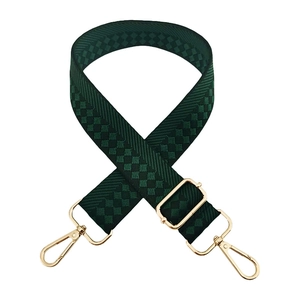 Macro view of checkered jacquard wide shoulder strap with dark green weaving and gold clips