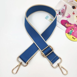 Detail of dark blue wide woven bag strap with golden metal hooks and adjustable buckle