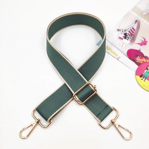 Detail of adjustable wide canvas shoulder strap in dark green with golden metal hooks