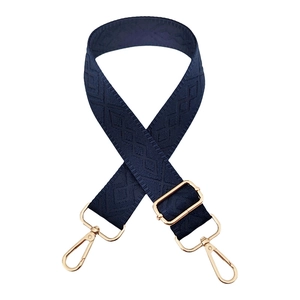 Detail of navy blue wide strap with diamond weave pattern and golden metal swivel hooks