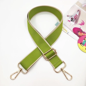 Detail of adjustable green and beige woven nylon bag strap with gold metal lobster clasp