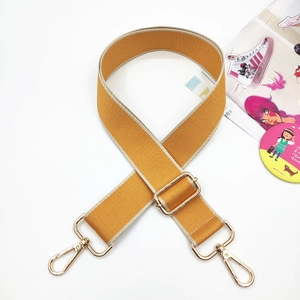Close-up of bright yellow woven adjustable bag strap with light gold metal hardware