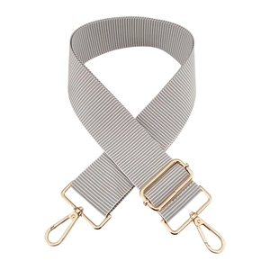 Adjustable grey and white striped bag strap with gold metal hooks on white background
