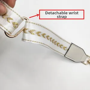 Close-up of detachable wrist strap with gold V-pattern embroidery and metal hook