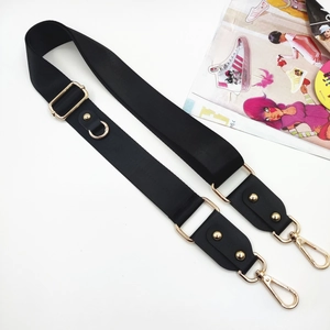Detail of adjustable black fabric crossbody strap with gold swivel hooks and leather ends