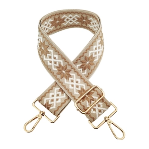 Detail of adjustable bohemian bag strap with beige geometric embroidery and gold buckle