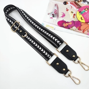 Adjustable black and white chevron pattern shoulder strap with gold metal hooks and leather trim