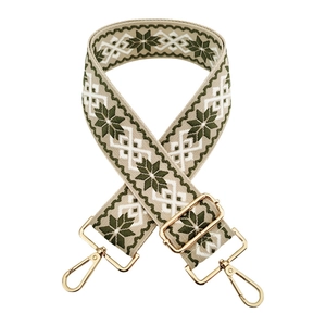 Detail of adjustable embroidered bag strap with green snowflake pattern and gold metal hooks