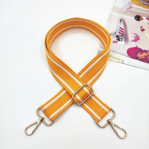 Detail eines verstellbaren 3,8cm gelb gestreiften Canvas-Taschenriemens mit Goldkarabiner