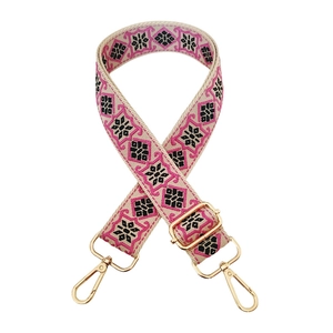 Detail of retro geometric embroidery on a wide bag strap with gold metal hooks