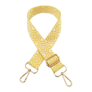 Detail of yellow and white geometric diamond woven bag strap with gold metal swivel hooks