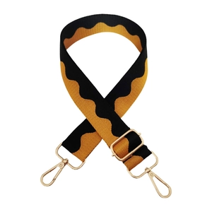 Detail of adjustable wave pattern bag strap with gold lobster clasps and metal buckle