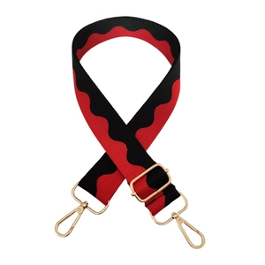 Detail of red and black wave patterned 3.8cm wide adjustable bag strap with gold hooks