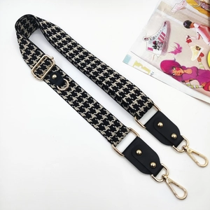 Close-up of adjustable houndstooth shoulder strap with gold hardware and leather ends
