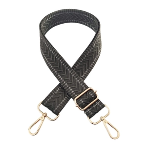 Detail of dark grey chevron pattern bag strap with adjustable gold metal hardware