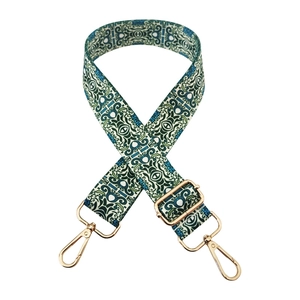 Detail of adjustable wide bag strap with vintage pattern and gold metal buckles