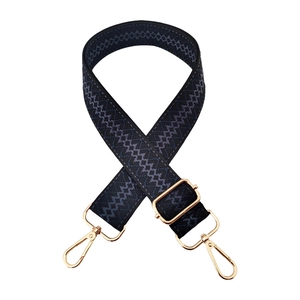 Macro detail of dark blue geometric jacquard bag strap with shiny gold lobster clasps