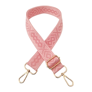 Close-up of pink geometric weave guitar style bag strap with light gold metal swivel hooks