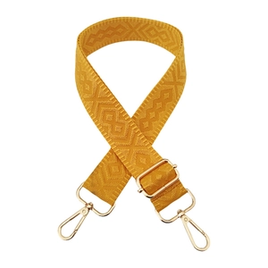 Macro detail of ginger yellow geometric jacquard bag strap with gold metal hooks