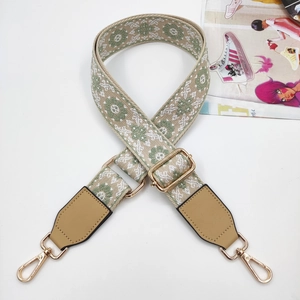 Close-up of ethnic style embroidered bag strap with golden metal hooks and hardware