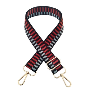 Detail of adjustable wide bag strap with colorful geometric pattern and gold buckles