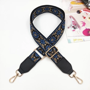 Close-up of ethnic embroidered bag strap with golden metal hooks and floral patterns