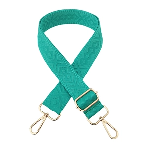 Detail of emerald green diamond patterned woven bag strap with golden metal hardware