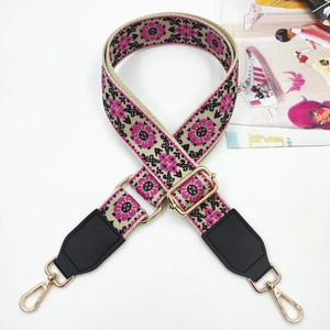 Close-up of ethnic embroidered bag strap with floral patterns and golden metal clasps
