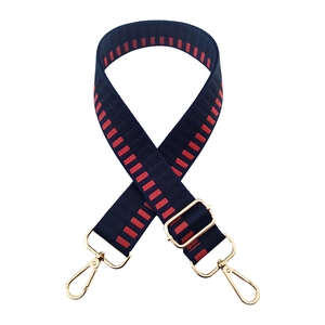 Detail of adjustable blue and red woven bag strap with gold metal hardware and lobster clasps