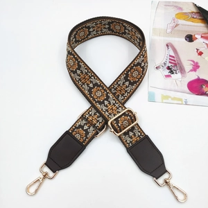 Detail of adjustable ethnic jacquard bag strap with vintage patterns and gold hardware