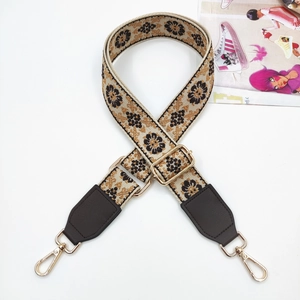 Close-up of ethnic style jacquard bag strap with floral pattern and gold hardware